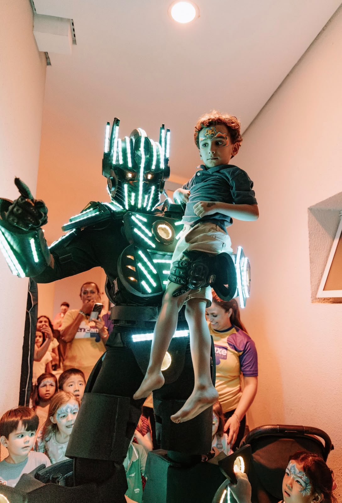 Robô de LED erguendo uma criança em festa de aniversário