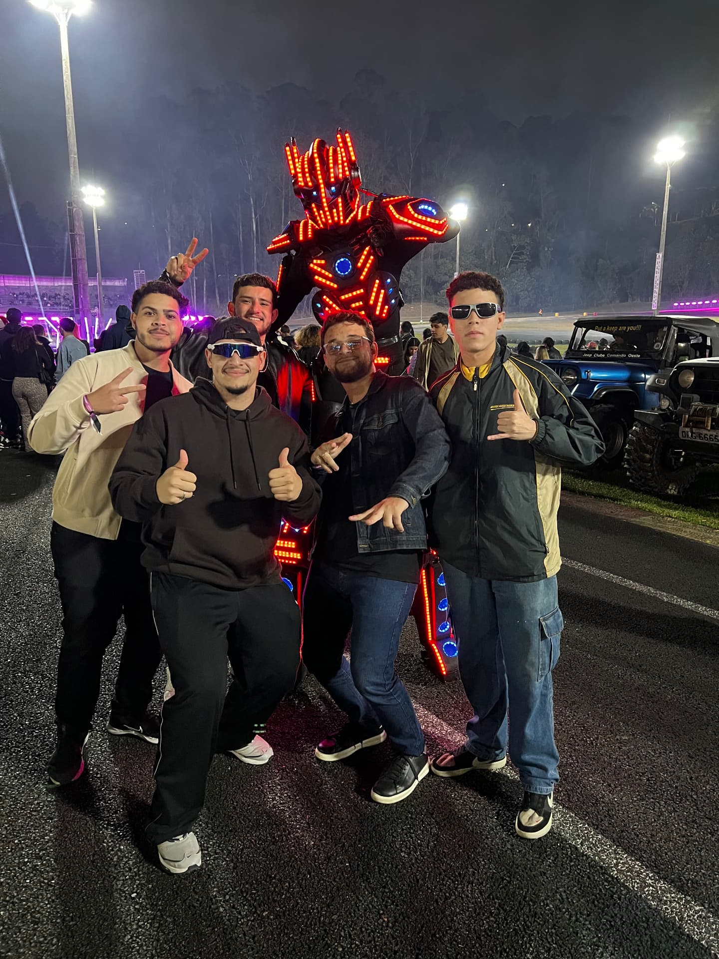 Grupo de amigos posando com o Robô de LED em evento ao ar livre
