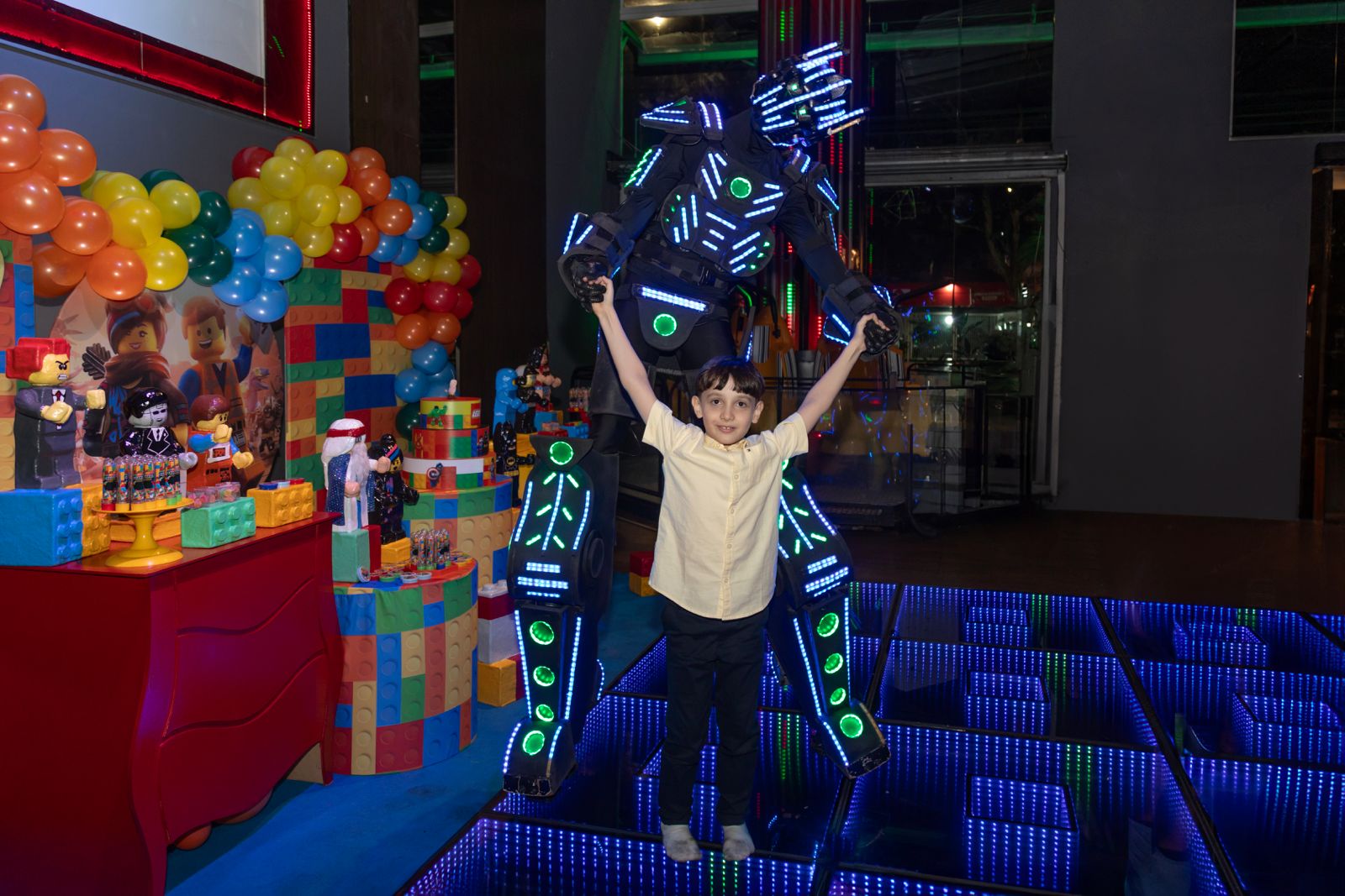 Criança comemorando ao lado do Robô de LED em festa temática