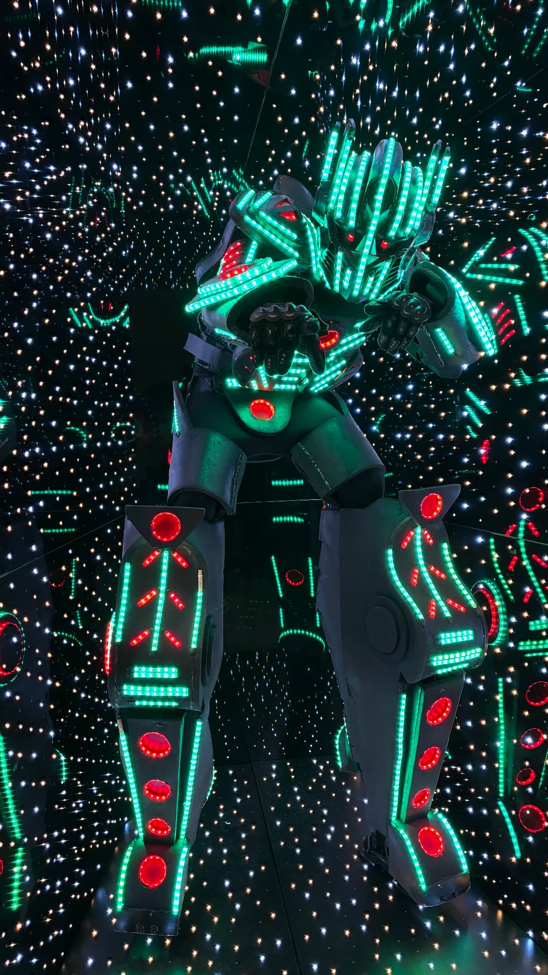 Robô de LED gigante iluminado em ambiente espelhado com luzes de festa
